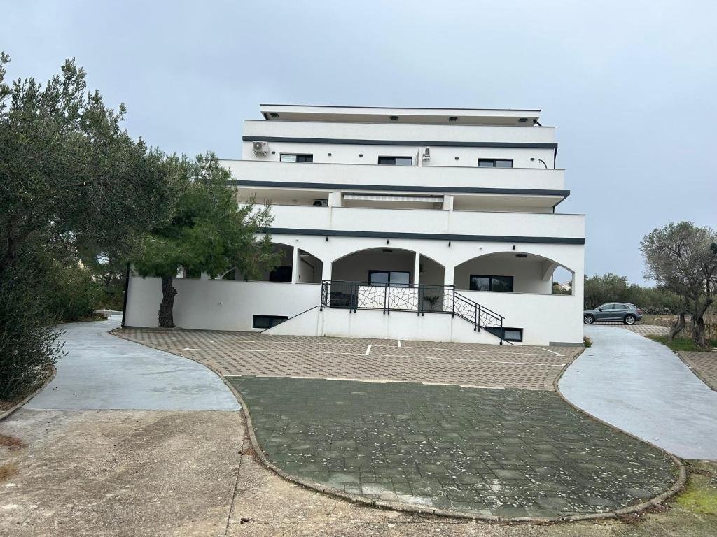 a white building with a driveway in front of it at Marepromo Jezera 1 in Jezera