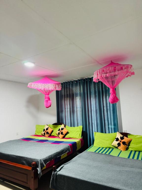 two beds in a room with pink umbrellas at PINI ROO Villa in Badulla