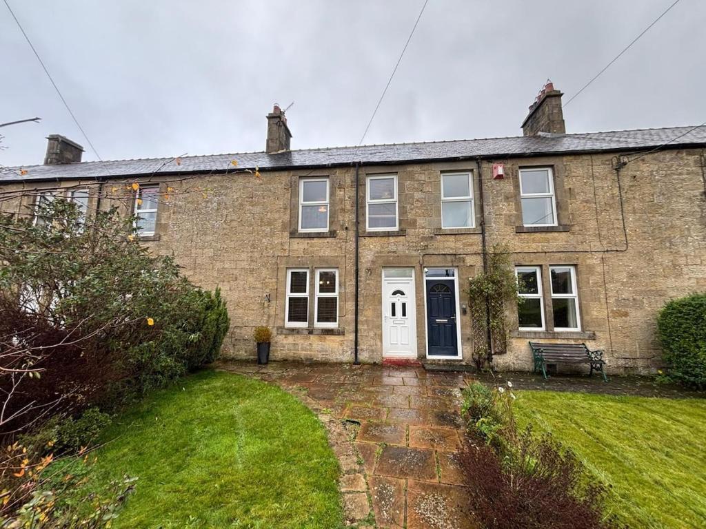 a brick house with a white door and a yard at 4, The Croft, Bellingham in Bellingham
