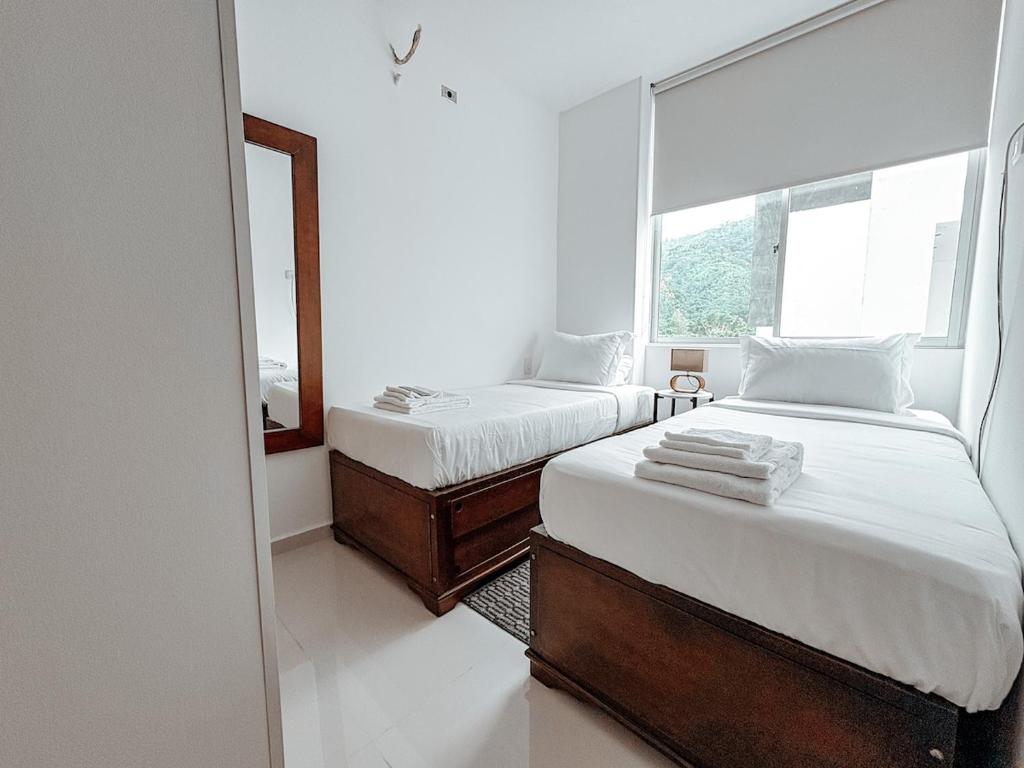 two beds in a room with a mirror and a window at Fee4Me Flat near Neomundo in Bucaramanga