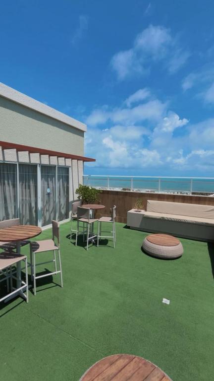 a patio with tables and chairs and the ocean at Ap Mirante Fortaleza 5min da Praia com Piscina e Rooftop para 6 pessoas in Fortaleza