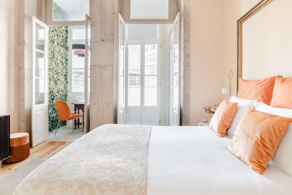 a bedroom with a large white bed with orange pillows at Get a Golden and Flower Flat in Porto