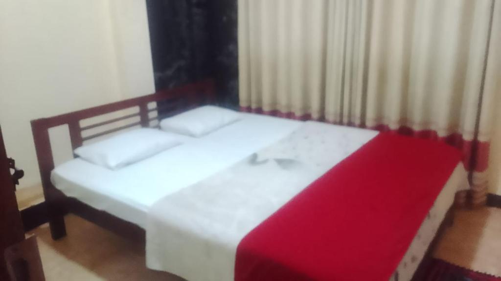 a bedroom with two beds and a red blanket at Ambewela Pattipola snowflak rest in Nuwara Eliya