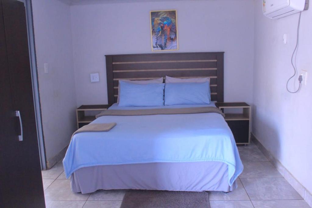 a bedroom with a large bed with blue sheets and pillows at Exodus Guesthouse Mahlakwena Stee'lpoort in Steelpoort