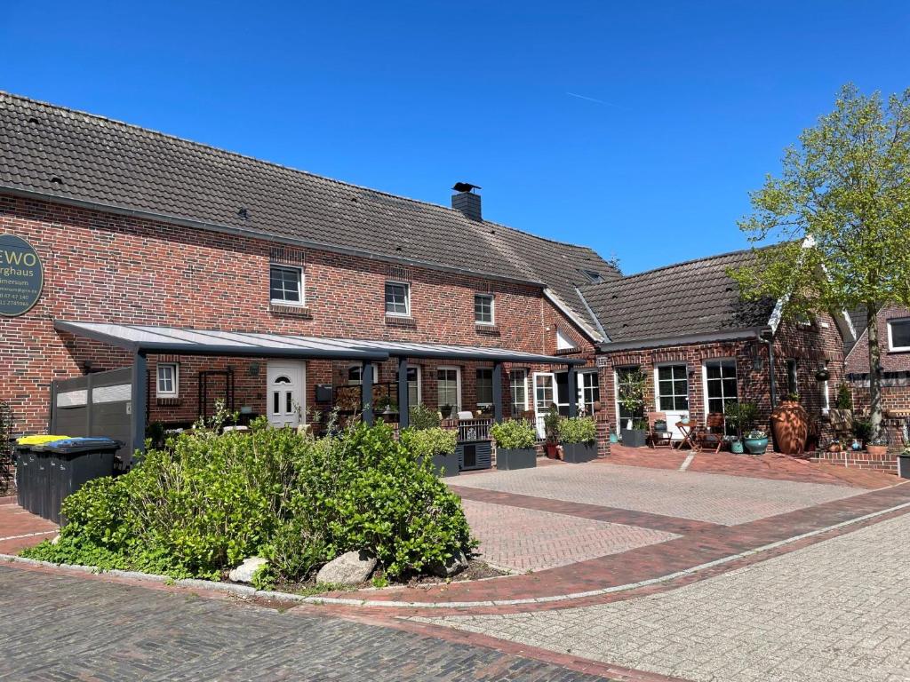a brick building with a courtyard in front of it at Wohnung Burghaus 1 EG in Krummhörn