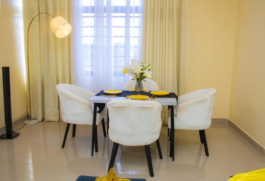 a dining room table with white chairs and a vase of flowers at Nook Cabins in Ruringʼu