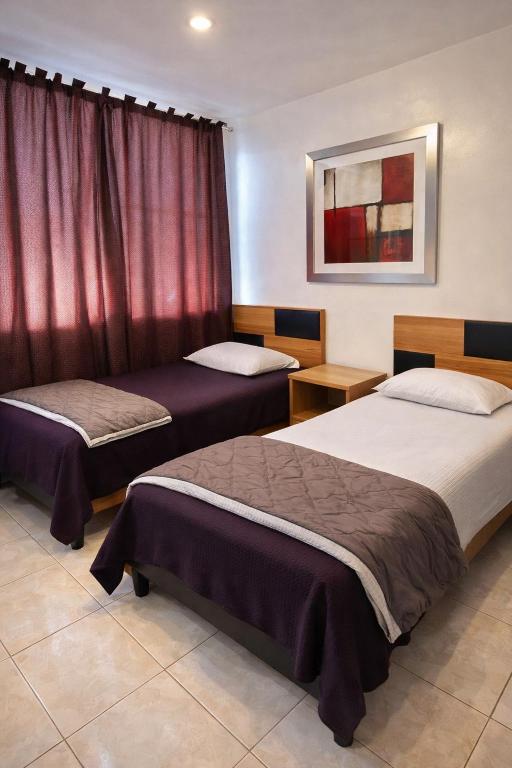 two beds in a hotel room with red curtains at Depa Centrico en Monterrey in Monterrey