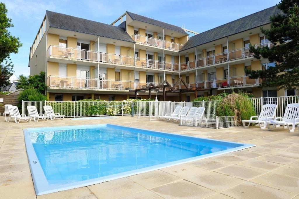 a hotel with a swimming pool in front of a building at Studio avec balcon, 4 personnes in Quiberon