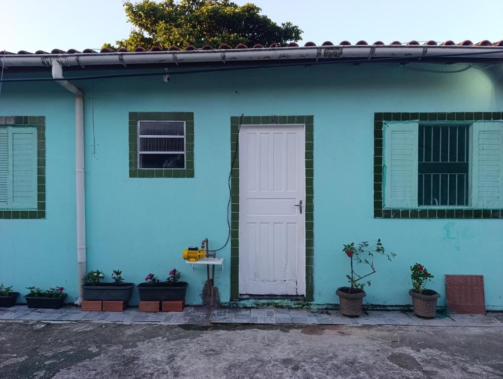 a blue house with a white door and some plants at Kit 400mts da praia in Bertioga