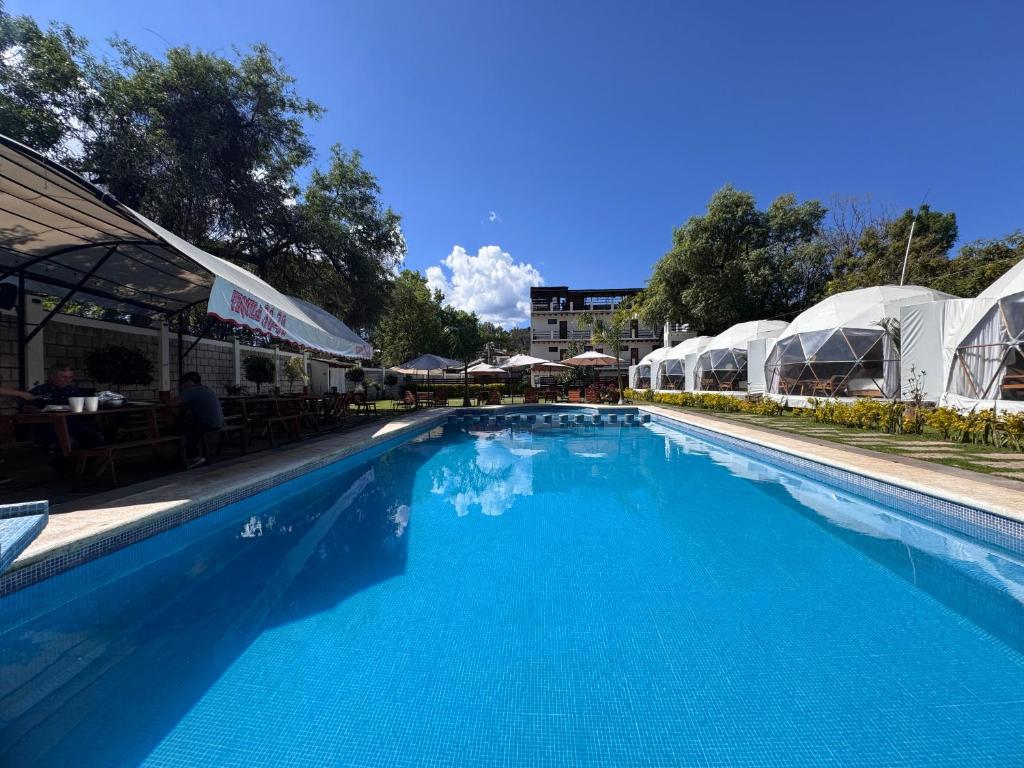 a large blue swimming pool with tables and umbrellas at Glamping en Valle de Bravo in Valle de Bravo