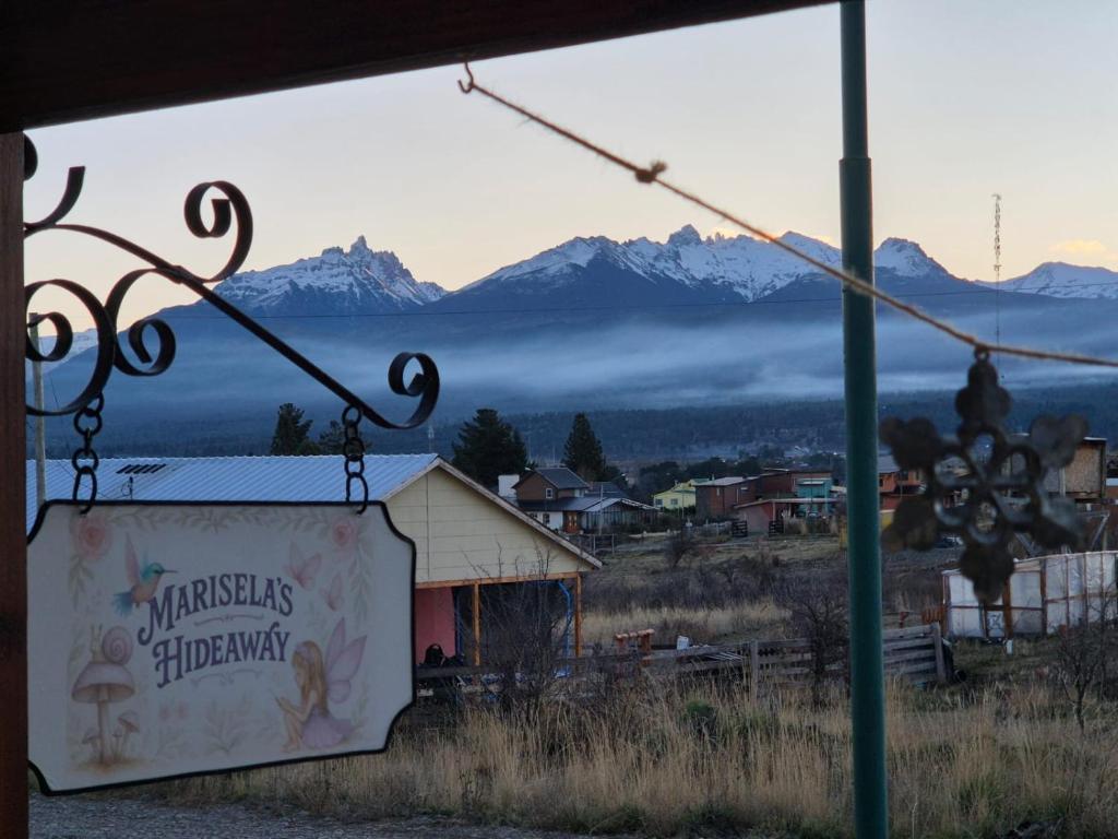a sign hanging from a building with mountains in the background at El refugio de Marisela in Trevelín