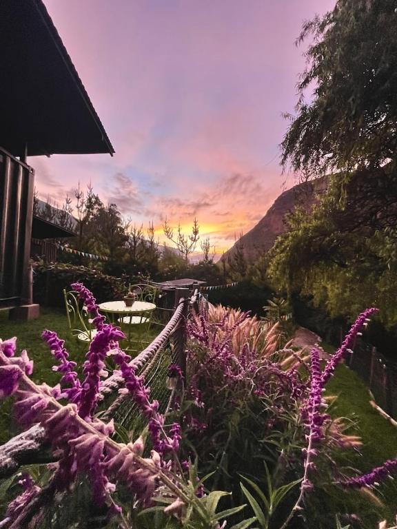 a garden with purple flowers in front of a sunset at Tiny Mountain River in Urubamba