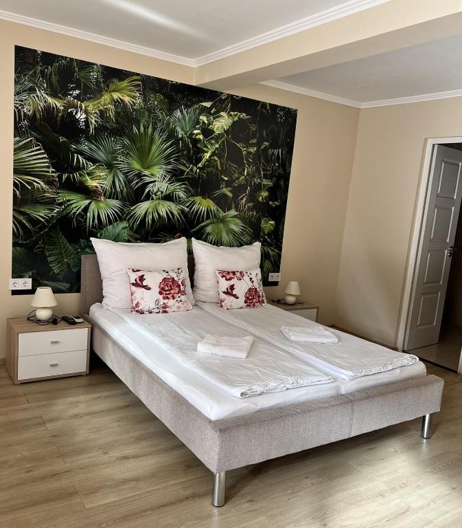 a bedroom with a bed with plants on the wall at Napfény Apartman in Makó