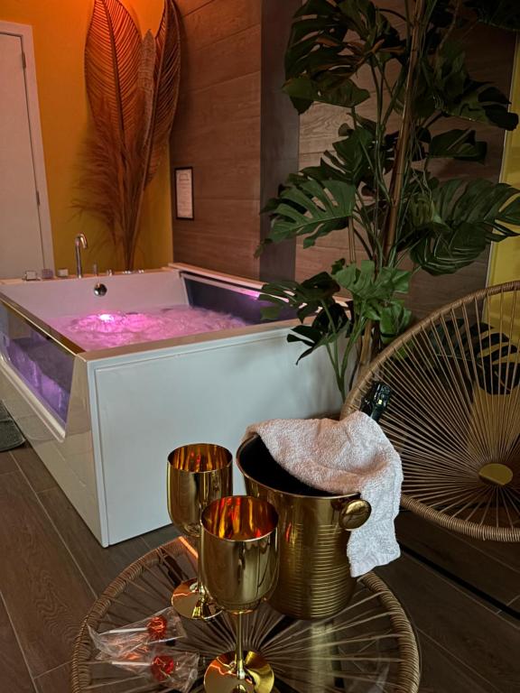 a bathroom with a tub with two glasses on a table at Le Bovary Hotel Suite Safari in Héron