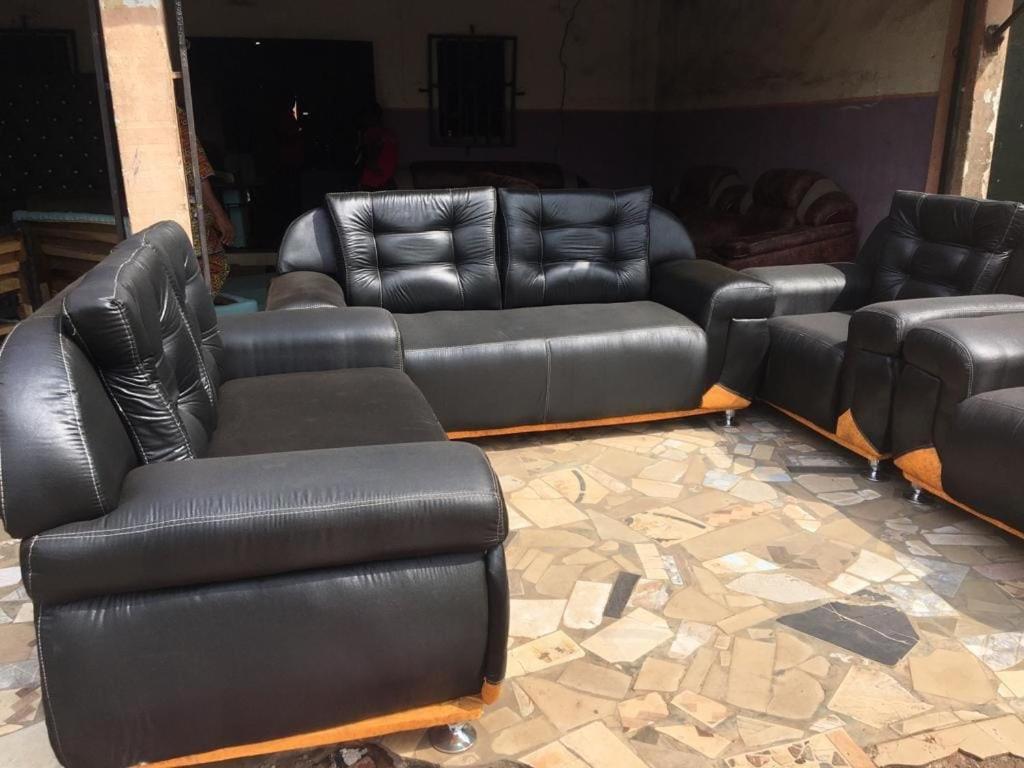 a living room with black leather couches and chairs at Trendy Terrace in Benin City