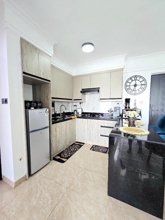 a large kitchen with white appliances and a clock on the wall at Padmore residence-Kilimani in Gatunga