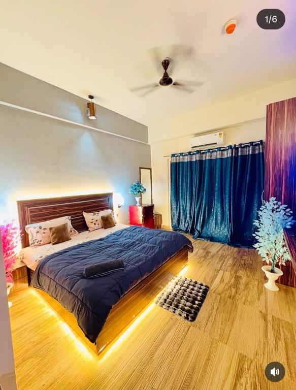 a bedroom with a large bed with blue curtains at Ocean Bloomz Stay in Greater Noida