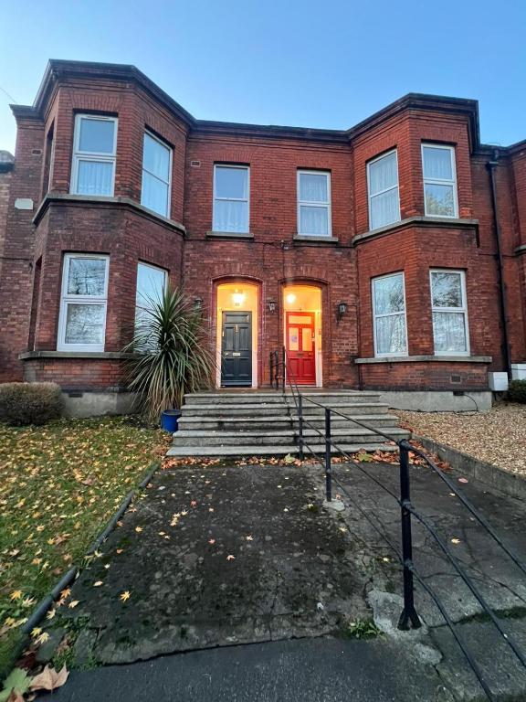 a brick house with a red door and stairs at ABC House in Dublin