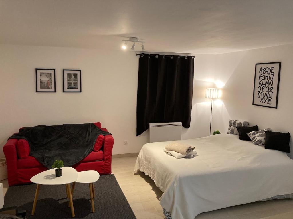 a bedroom with a bed and a red chair at Apartment avec cours in Bonny-sur-Loire