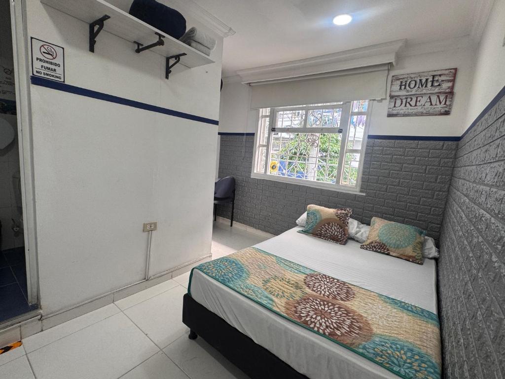a bedroom with a bed in a room with a window at Casa Hotel Manco Mora in Medellín