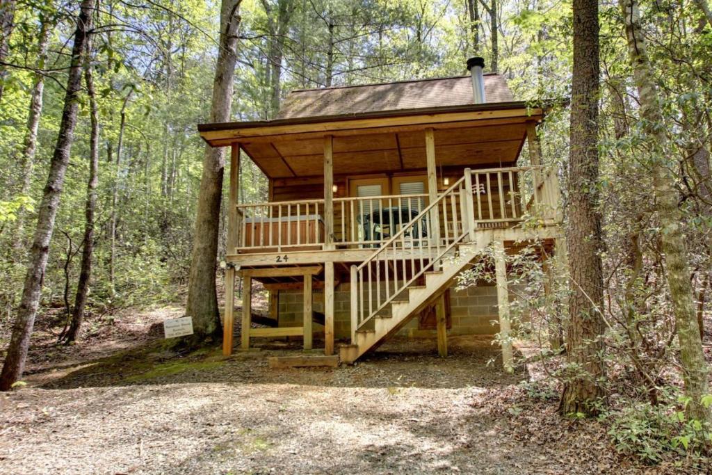 a tree house in the woods with a staircase at Bavarian Hideaway 24 in Sautee Nacoochee
