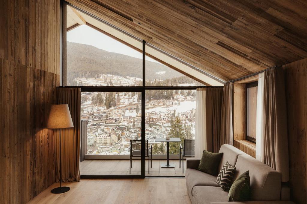 a living room with a couch and a large window at Luxury B&B August in Ortisei