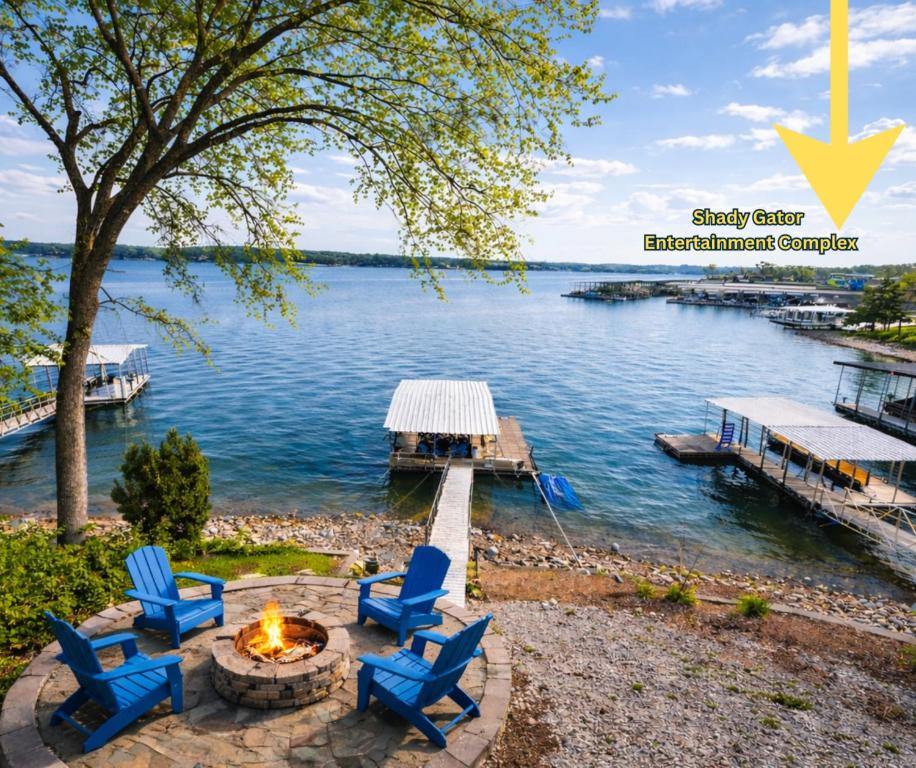 a group of blue chairs around a fire pit next to the water at Sunset and Chill Lakefront 3 Bed 2 Bath Hottub, Firepit Dock in Lake Ozark