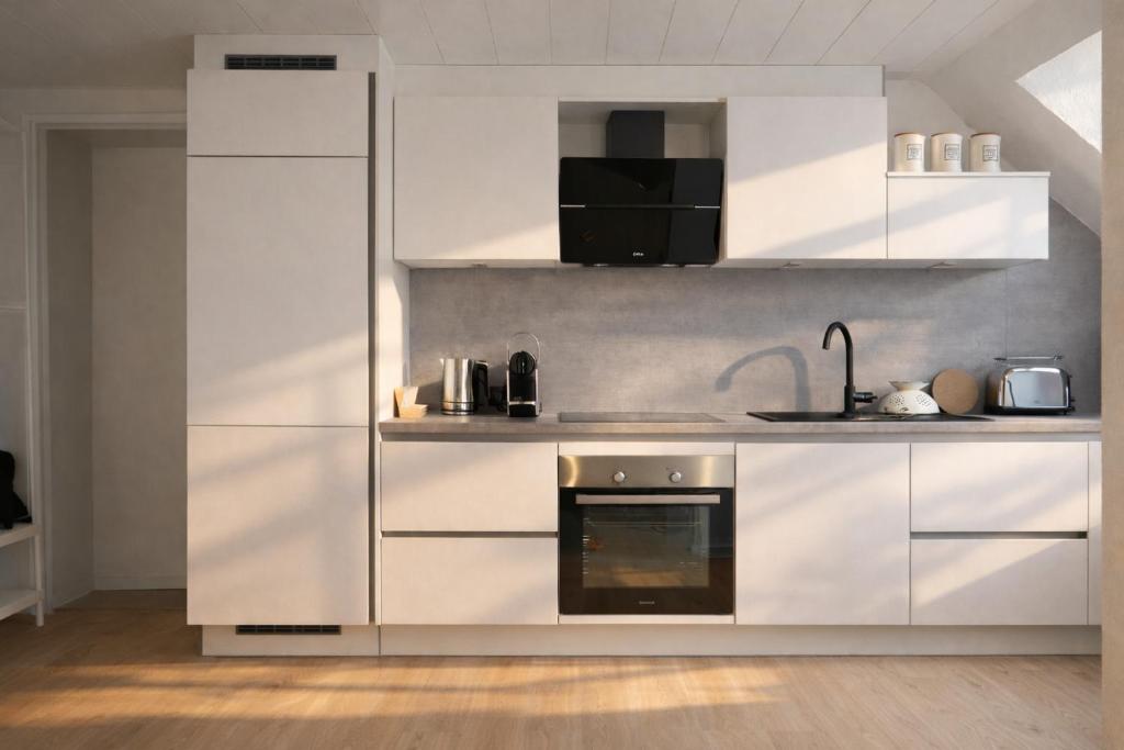 a kitchen with white cabinets and a stove at Ostfrieschen Ferienwohnung & Spielscheune in Oldendorf