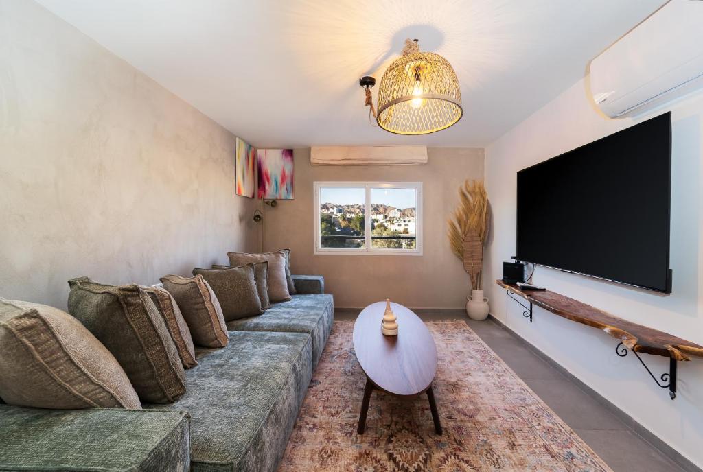a living room with a couch and a flat screen tv at אשראם-Ashram Eilat in Eilat