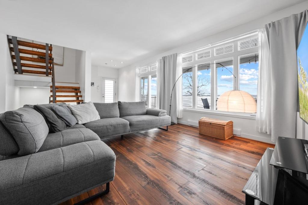a living room with a couch and a large window at A Getaway on Lake Champlain in Venise-en-Québec