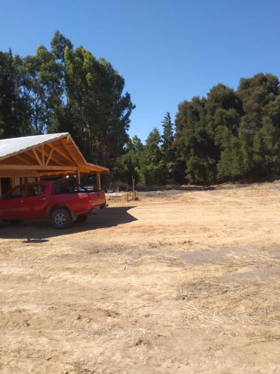 a red truck parked in a field with a tent at Cabaña con rio y camping in Los Ángeles