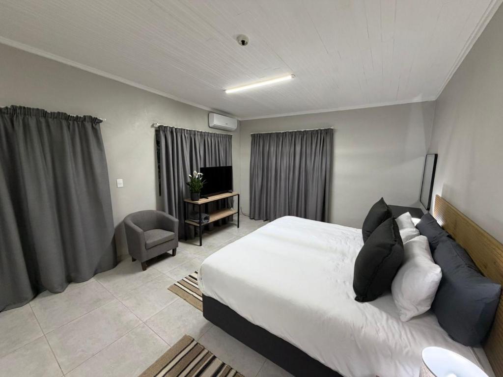 a bedroom with a bed and a chair and a television at Green Haven Waitara in Tzaneen