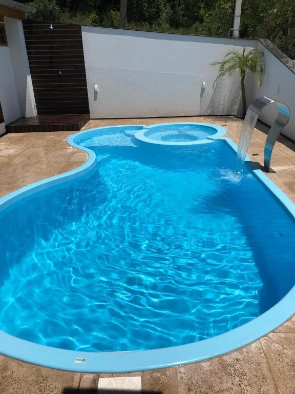 a large blue pool with a water fountain at Casa da Palmeira com Piscina in Piratuba