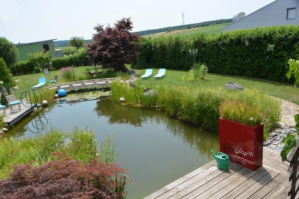 a pond in a garden with a wooden deck at Designer Apartement mit Kamin in Hartberg