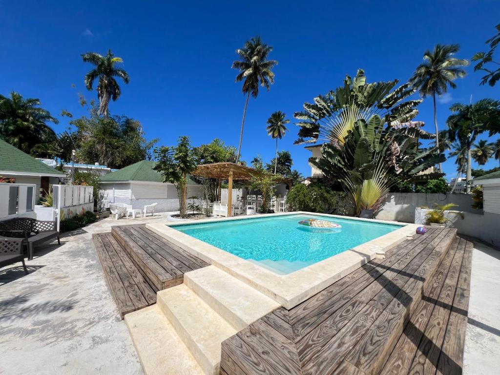 a swimming pool in a backyard with palm trees at Hostel La Bohème in Las Terrenas
