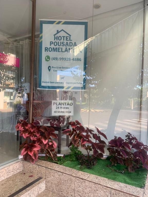 a sign in a store window with some plants at Pousada Romelandia in Romelândia