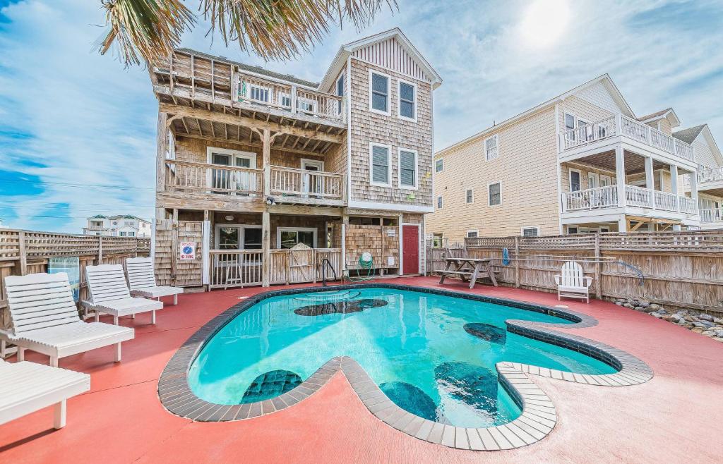 a swimming pool in front of a house at Happy Dog Days - Nags Head MP 11, Ocean View, 50 Yds to Beach, Elevator, Pool, Hot Tub, Pets OK, Flex Stays in Nags Head