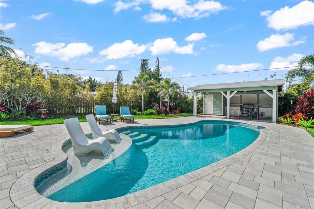 a swimming pool with two chairs and a house at Private Pool, Backyard, and Steps to the Beach in Cocoa Beach