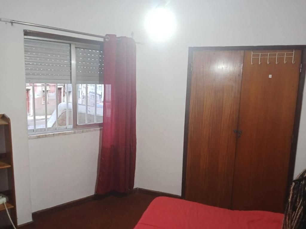 a bedroom with a door and a red curtain at apartamento com varios quartos in Coimbra