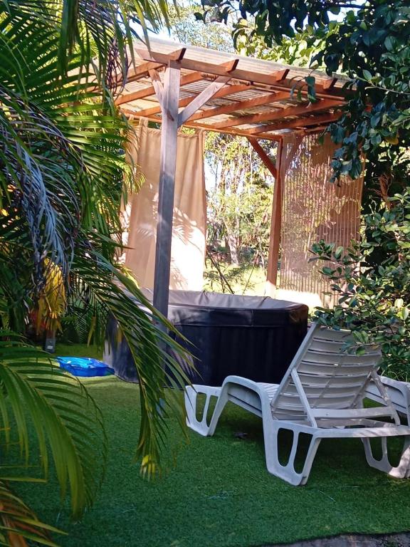 a white chair sitting under a wooden pergola at Bungalow nature zen in Le Gosier