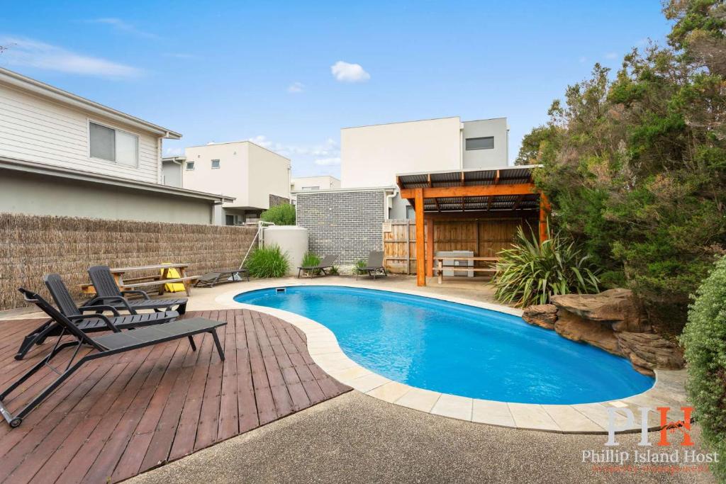 a backyard with a swimming pool and two chairs and a house at Townhouse with Shared Pool in Cowes in Cowes