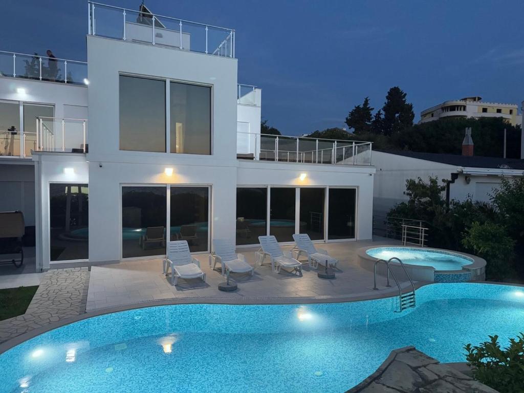 a villa with a swimming pool in front of a house at Sea Whisper Villa in Dobra Voda