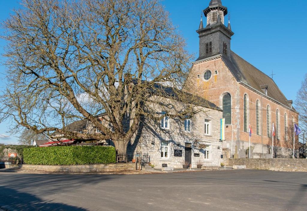a church with a tree in front of it at B&B - Hotel Le vieux marronnier in Foy-Notre-Dame
