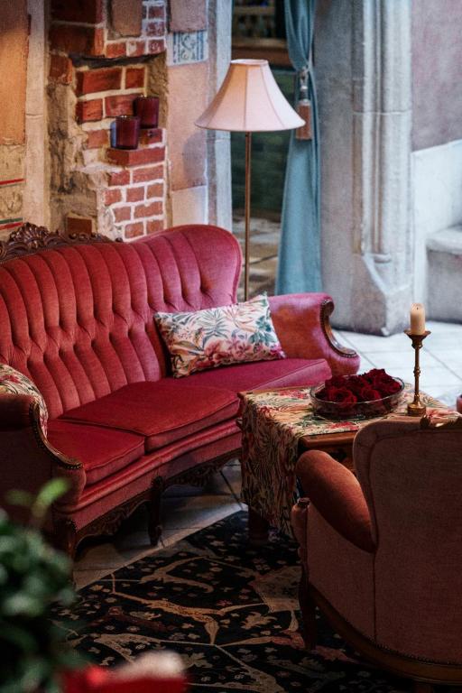 a living room with a red couch and a table at Butikowy Hotel Zameczek in Książ Wielki