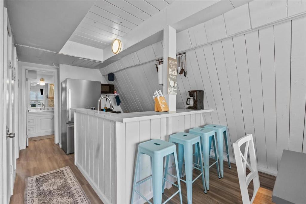 a kitchen with blue stools in front of a counter at Sleep Over the Ocean in Surfside Beach