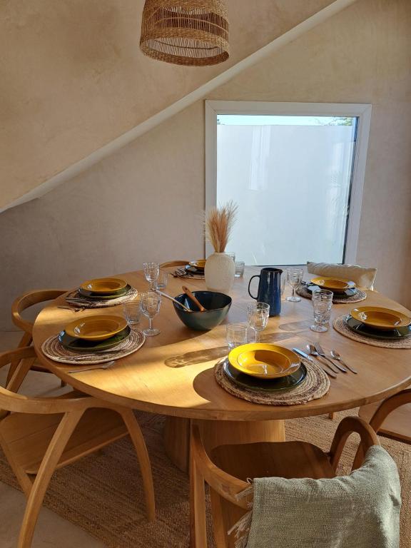 a wooden table with plates and glasses on it at Villa Face a l'océan- Havre de paix & grand confort avec piscine à TOUBAB DIALAW in Rufisque