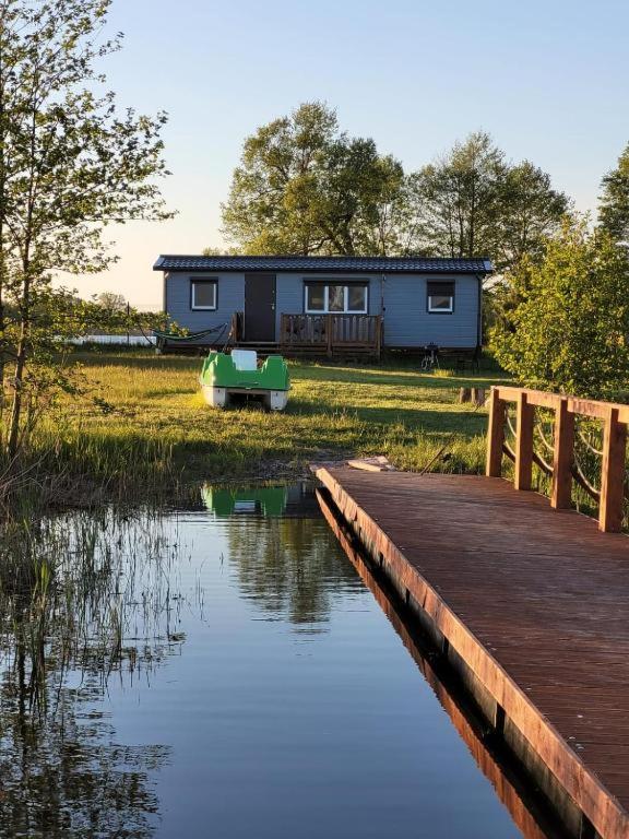 a house with a dock and a boat on the water at Domki nad Szóstakiem in Orzechowo