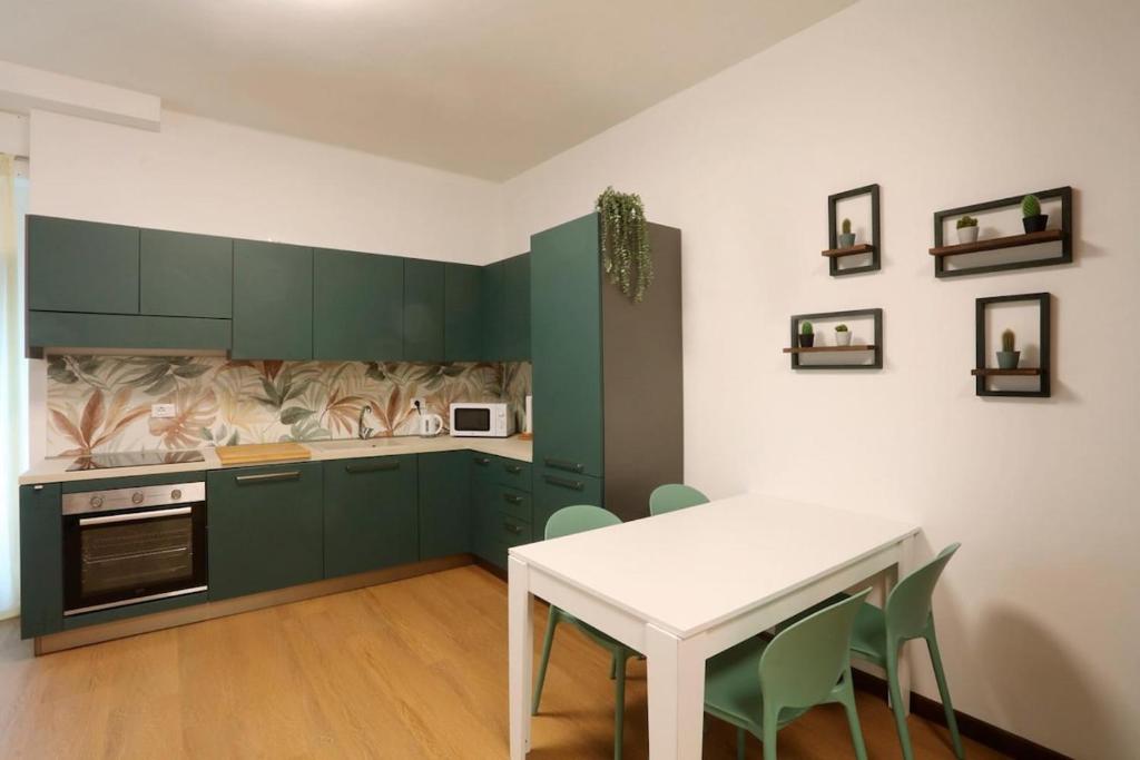 a kitchen with green cabinets and a white table at Solferino Green - Modern Stay - Near station in Brescia
