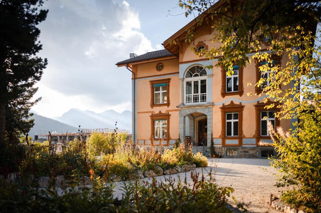 a large orange house with mountains in the background at Villa Klainguti in Pontresina