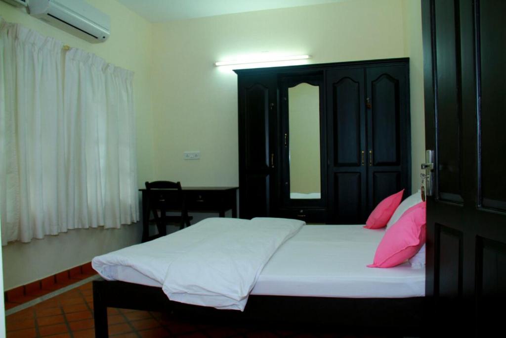 a bedroom with a large bed with pink pillows at Malakkarethu House in Aranmūla